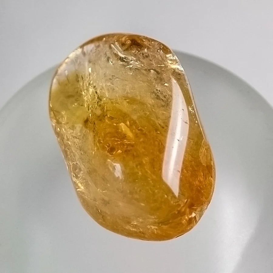 Real tumble-polished citrine photographed on a light background